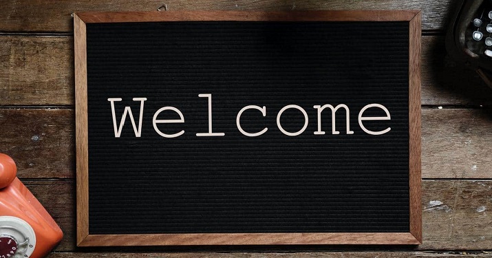 Black chalkboard with white "Welcome" text on a brown desk